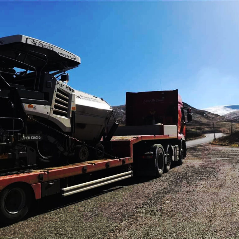Trevor Harris Vogele 1303 on the back of the loader, road leading to hills in the distance